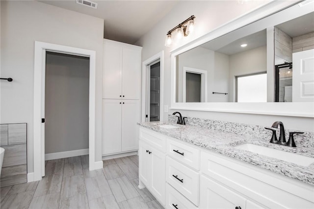 full bathroom with double vanity, visible vents, a shower stall, and a sink