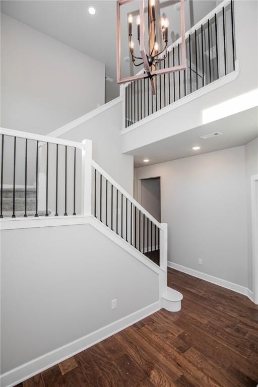 stairs featuring wood finished floors, baseboards, a high ceiling, recessed lighting, and a chandelier