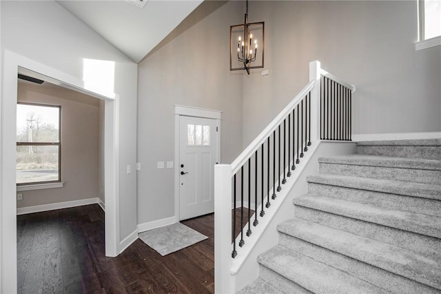 entrance foyer featuring an inviting chandelier, high vaulted ceiling, stairs, baseboards, and wood finished floors