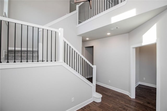 stairs with recessed lighting, baseboards, wood finished floors, a towering ceiling, and visible vents