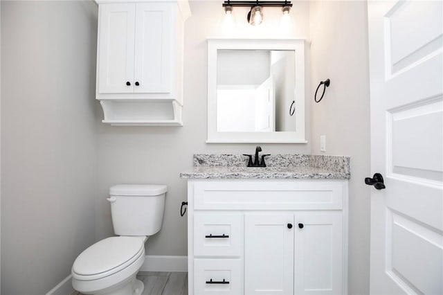 bathroom featuring vanity, baseboards, and toilet