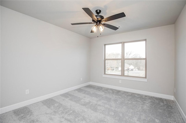carpeted spare room featuring baseboards and a ceiling fan