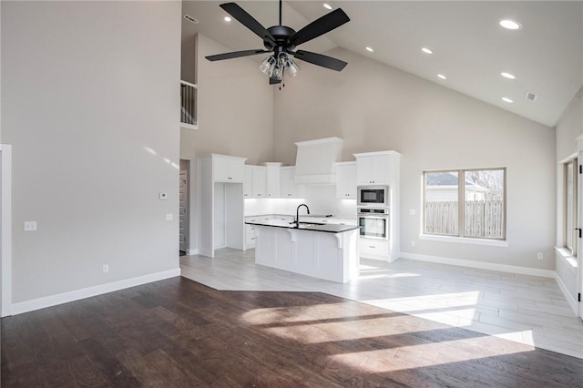 unfurnished living room featuring baseboards, high vaulted ceiling, recessed lighting, light wood-type flooring, and a ceiling fan