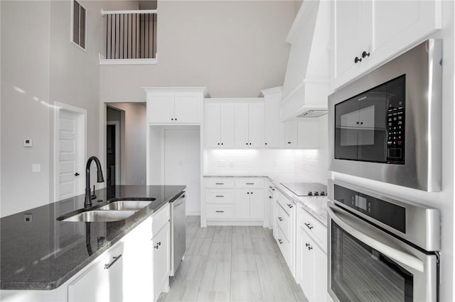 kitchen featuring visible vents, a high ceiling, a center island with sink, a sink, and appliances with stainless steel finishes
