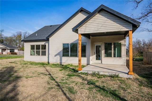 back of house featuring a lawn, a shingled roof, a patio area, and fence