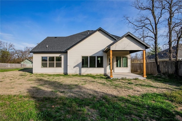 back of property with a lawn, a patio, a fenced backyard, and roof with shingles