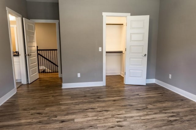 unfurnished bedroom featuring dark hardwood / wood-style flooring, a spacious closet, and a closet