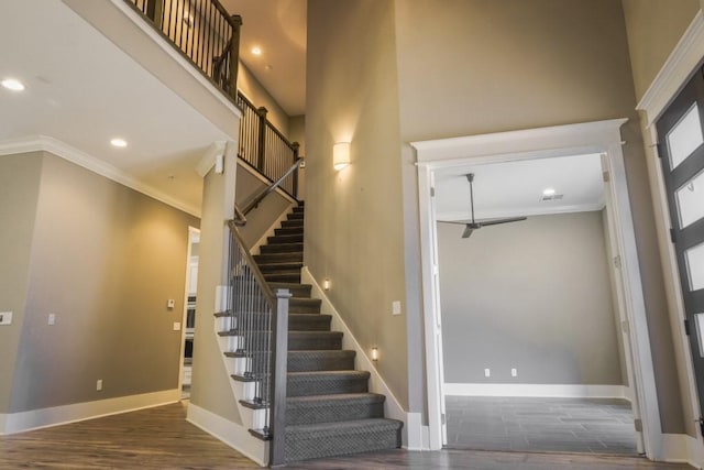 stairs featuring hardwood / wood-style flooring, ornamental molding, and a high ceiling