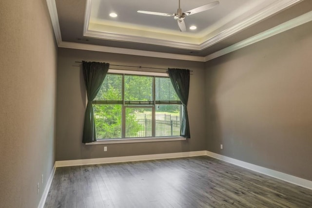 unfurnished room with a tray ceiling, ceiling fan, crown molding, and dark hardwood / wood-style floors