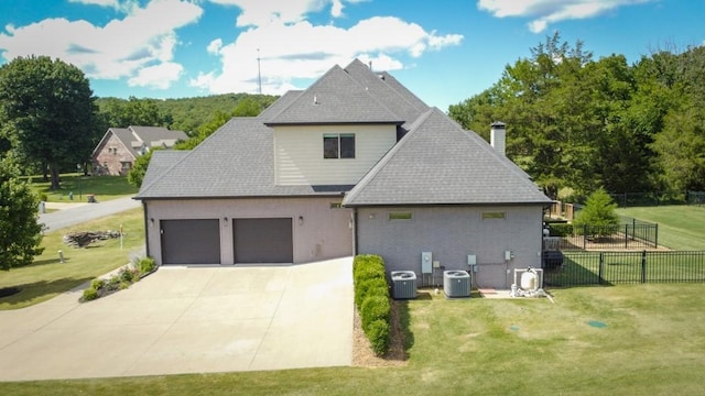 rear view of property with a lawn, cooling unit, and a garage