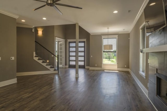 unfurnished living room featuring ceiling fan, dark hardwood / wood-style flooring, crown molding, and a fireplace