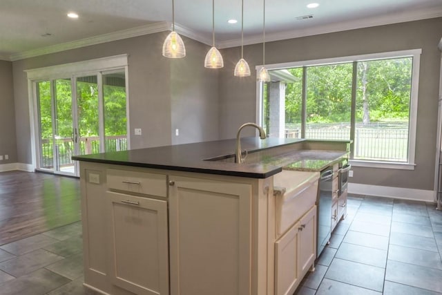 kitchen with a kitchen island with sink, crown molding, oven, and pendant lighting