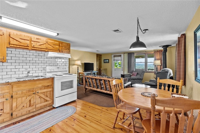 kitchen featuring hanging light fixtures, a textured ceiling, light wood-type flooring, white electric range oven, and sink