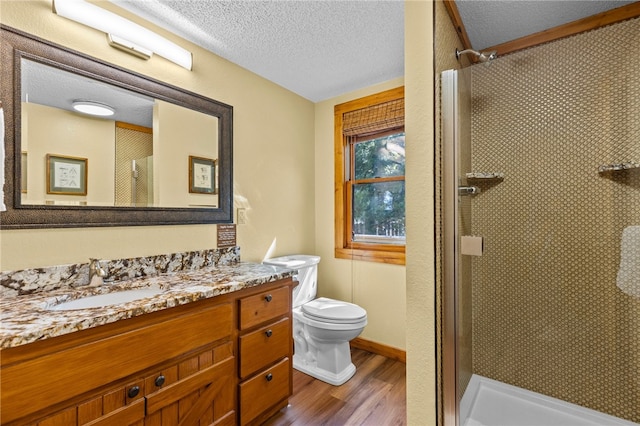 bathroom featuring walk in shower, a textured ceiling, hardwood / wood-style flooring, vanity, and toilet