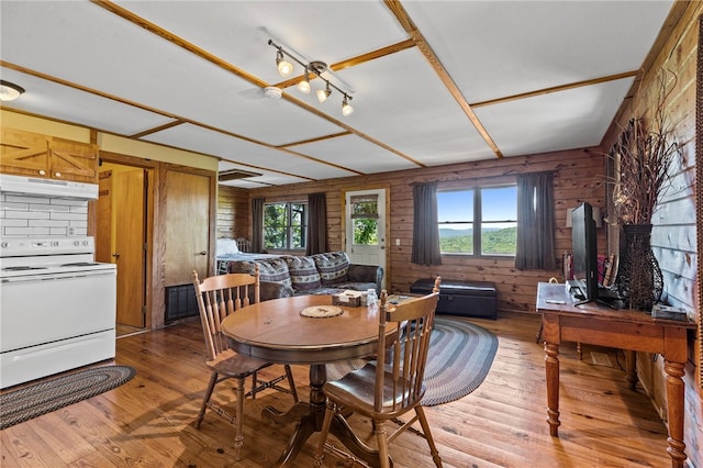 dining room with wood-type flooring, a healthy amount of sunlight, and wooden walls