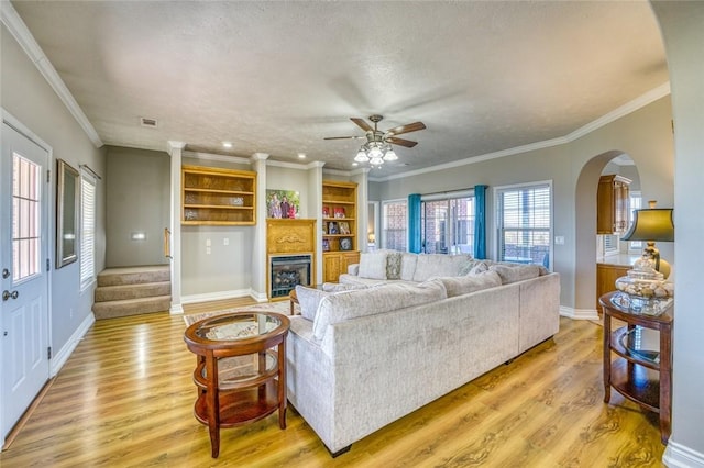 living room with crown molding, ceiling fan, light hardwood / wood-style floors, and a textured ceiling