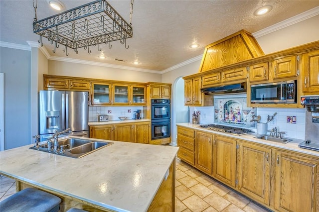 kitchen with appliances with stainless steel finishes, sink, light tile patterned floors, and an island with sink