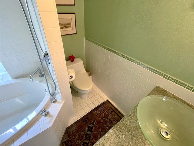 bathroom with tile flooring, sink, tiled bath, and toilet