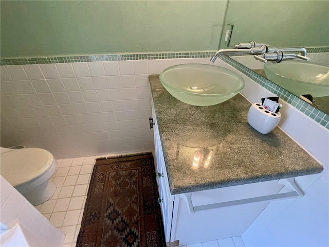 bathroom with tile walls, tile flooring, toilet, and oversized vanity