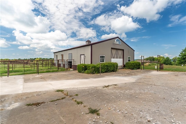 view of side of property featuring a rural view and an outdoor structure