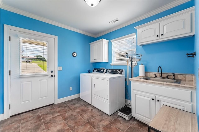 clothes washing area with washer and clothes dryer, cabinets, crown molding, sink, and plenty of natural light