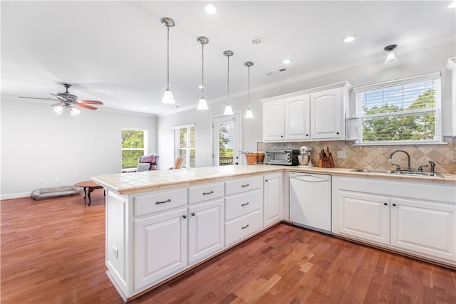 kitchen with white cabinetry, sink, hanging light fixtures, kitchen peninsula, and white dishwasher