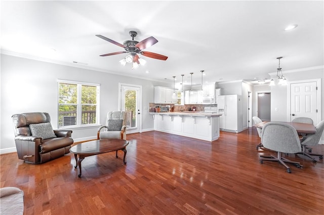 living room with ceiling fan with notable chandelier, dark hardwood / wood-style flooring, and ornamental molding