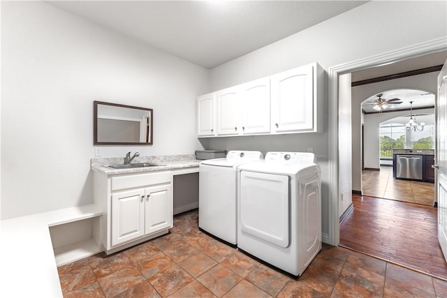 laundry area featuring ceiling fan with notable chandelier, cabinets, sink, and washing machine and clothes dryer