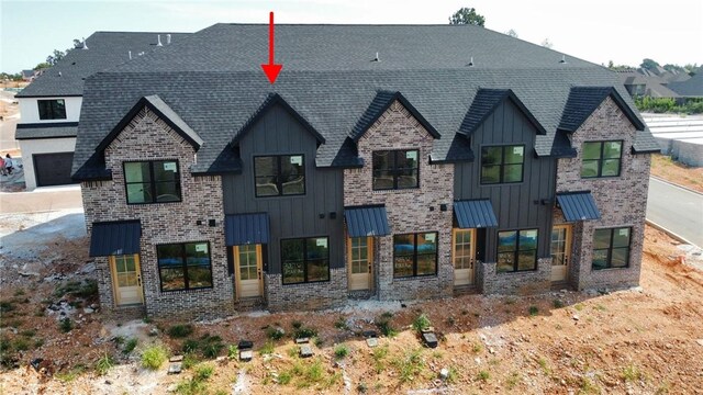 view of front facade with brick siding, board and batten siding, and a standing seam roof