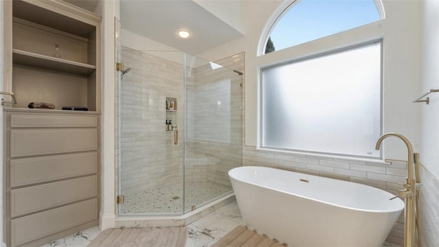 bathroom featuring a healthy amount of sunlight, tile walls, and shower with separate bathtub