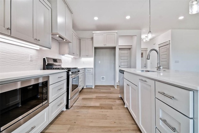 kitchen featuring white cabinetry, sink, stainless steel appliances, light hardwood / wood-style flooring, and decorative light fixtures