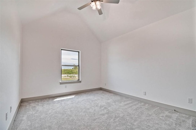 spare room with light colored carpet, vaulted ceiling, and ceiling fan