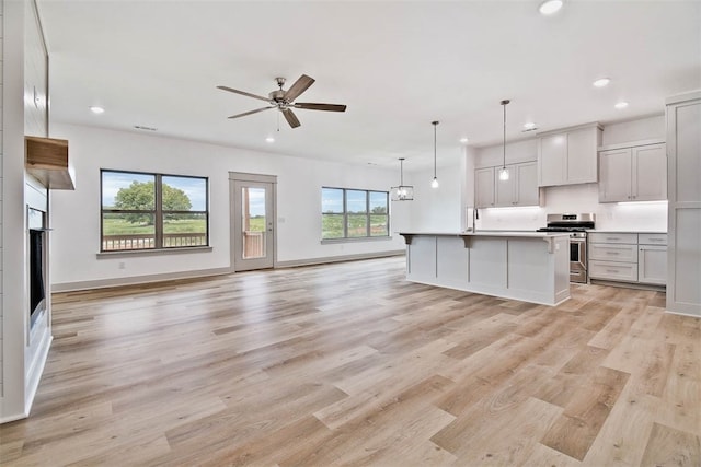 kitchen featuring gas stove, a kitchen island with sink, a breakfast bar, and a healthy amount of sunlight