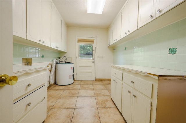 laundry area with water heater, washer hookup, light tile patterned flooring, and cabinets