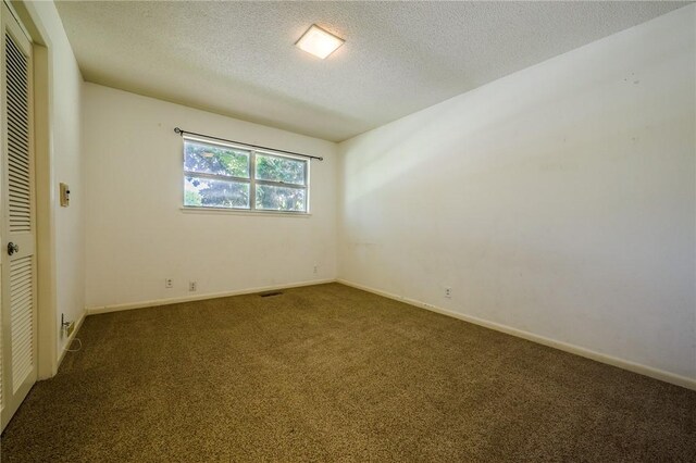 carpeted empty room featuring a textured ceiling