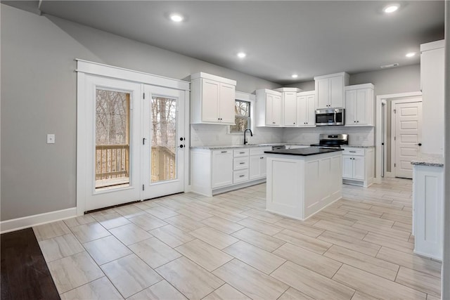 kitchen featuring stainless steel appliances, a center island, white cabinets, and tasteful backsplash