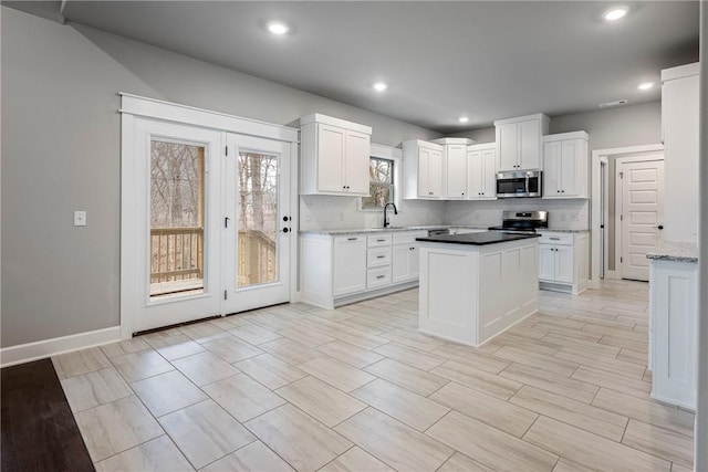 32 Taransay Dr, Bella Vista, AR 72715 - kitchen with a kitchen island, white cabinets, decorative backsplash, and stainless steel appliances