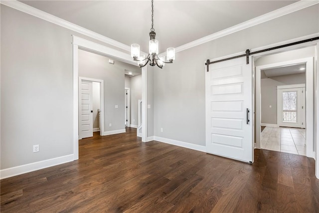 unfurnished dining area featuring wood finished floors, crown molding, baseboards, and a barn door