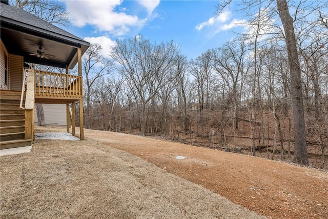 view of yard with a ceiling fan, a wooden deck, and stairs