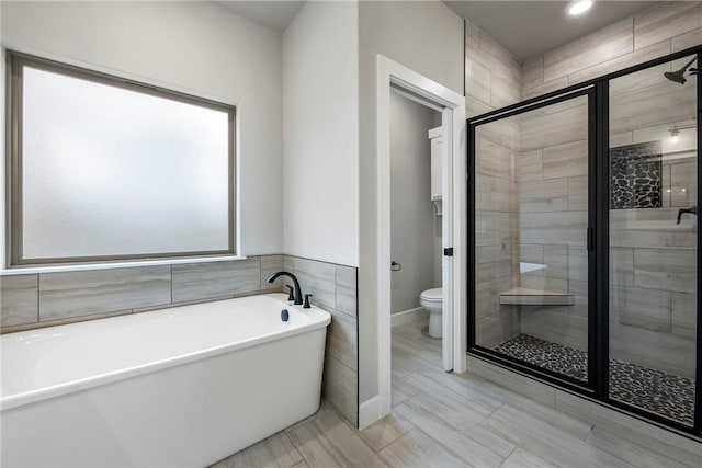 full bathroom featuring toilet, a shower stall, and a freestanding bath