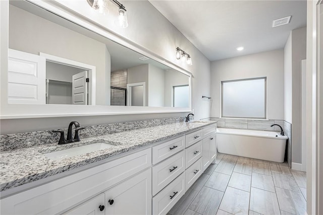 full bathroom with a washtub, a sink, visible vents, double vanity, and a stall shower