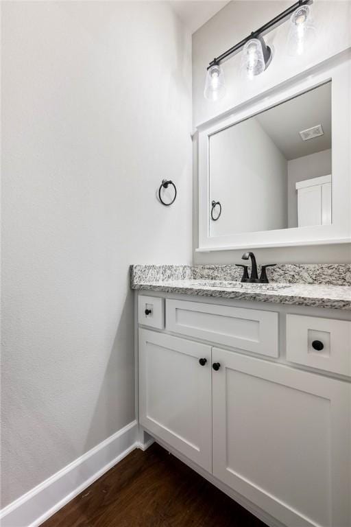 bathroom with visible vents, wood finished floors, vanity, and baseboards