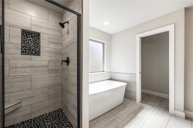 full bath with a stall shower, baseboards, and a freestanding tub