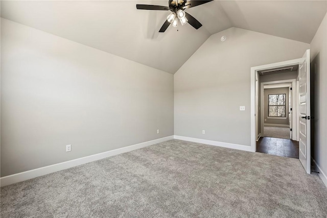 spare room with vaulted ceiling, dark colored carpet, a ceiling fan, and baseboards