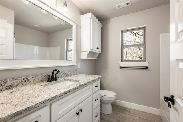 bathroom featuring toilet, wood finished floors, vanity, visible vents, and baseboards