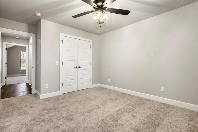 unfurnished bedroom with a closet, carpet, a ceiling fan, and baseboards