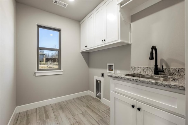 washroom with hookup for an electric dryer, washer hookup, a sink, visible vents, and cabinet space