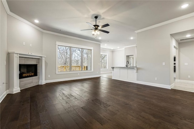 unfurnished living room with dark wood-style floors, ceiling fan, a tiled fireplace, and baseboards