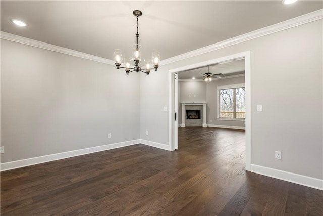 interior space with a fireplace, dark wood-type flooring, ornamental molding, baseboards, and ceiling fan with notable chandelier