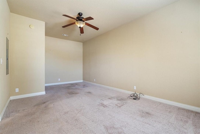 empty room with ceiling fan, light colored carpet, and electric panel